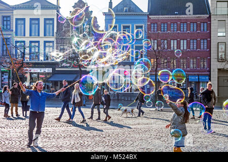 Street Performer/Gaukler blasen riesige Seifenblasen mit Schleifen in String zwischen zwei Stöcke statt Kinder auf dem Marktplatz in der Stadt zu unterhalten Stockfoto