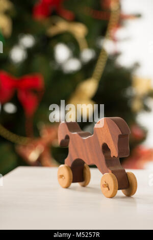 Vintage Wooden Horse auf Santa's Arbeitstisch, Weihnachtsbaum auf Hintergrund Stockfoto