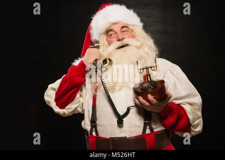 Portrait von Santa Claus die Telefonnummer gegen den dunklen Hintergrund Stockfoto