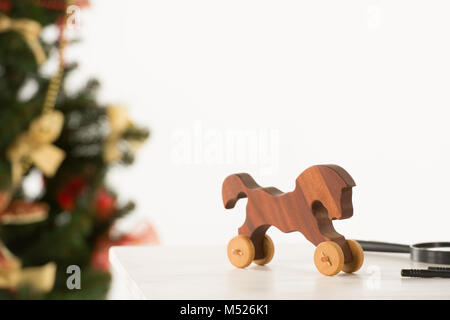 Vintage Wooden Horse auf Santa's Arbeitstisch, Weihnachtsbaum auf Hintergrund Stockfoto