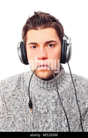 Closeup Portrait der traurige junge Mann mit inländischen Pullover Holding kabel Kopfhörer in seinem Mund und Kamera Stockfoto