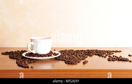 Dramatische Foto Weltkarte made of Kaffeebohnen. Weiße Tasse mit Heißgetränk Stockfoto