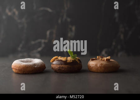 Drei Donuts auf dunklem Stein Stockfoto