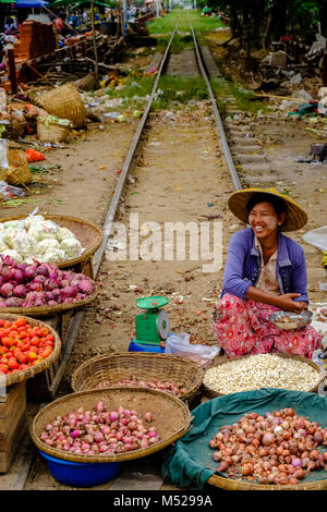 Eine Frau verkauft, Zwiebeln und Tomaten aus Bambus Körbe in den Markt von Stadt, sitzen auf einer Bahnstrecke Stockfoto