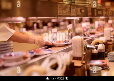 Nahaufnahme einer Hand Sushi Chef eine Platte von Sushi auf ein Förderband Musashi Sushi, berühmten Förderband Sushi Restaurant, Kaitenzushi, in Ky Stockfoto