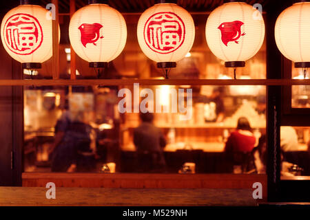 Leute drinnen ein traditionelles japanisches Restaurant mit Laternen nachts beleuchtet. Gion, Kyoto, Japan 2017. Stockfoto