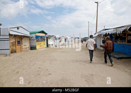 Migranten Spaziergang durch das Camp in Calais, wo Tausende leben würden, in der Hoffnung, immer nach Großbritannien, bevor es abgerissen wurde. Das Calais Dschungel war eine illegale Ansiedlung von Flüchtlingen und Migranten in der Nähe der Stadt Calais im Norden Frankreichs. Die Flüchtlinge und Migranten beschließen, dort zu begleichen, da es in der Nähe des Euro Tunnel, die das Vereinigte Königreich mit dem europäischen Festland verbinden und sie warteten auf ihre Chancen zu, die in Großbritannien durch das Verstecken in Lastwagen, in Richtung Großbritannien. Das Calais Dschungel Siedlung wurde schließlich durch die französische Regierung im Oktober 2016 abgerissen. Stockfoto