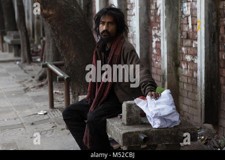 Ein Obdachloser sitzt seine Habseligkeiten auf einer Bank in der Hauptstadt. Dhaka, die Hauptstadt Bangladeschs liegt am Ostufer des Buriganga River im Herzen der Bengal delta. Die Stadt ist ein Mikrokosmos des ganzen Landes, mit den verschiedenen religiösen und ethnischen Gemeinschaften. Dhaka ist die wirtschaftliche, kulturelle und politische Zentrum von Bangladesch und ist ein bedeutender Finanzplatz in Südasien. Es ist eines der am dichtesten besiedelten Städte der Welt mit einer Bevölkerung von 18.89 Millionen Menschen im Großraum Dhaka. Stockfoto