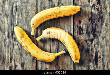 Bananen. Drei reife Bananen auf einer hölzernen Tisch. Stockfoto