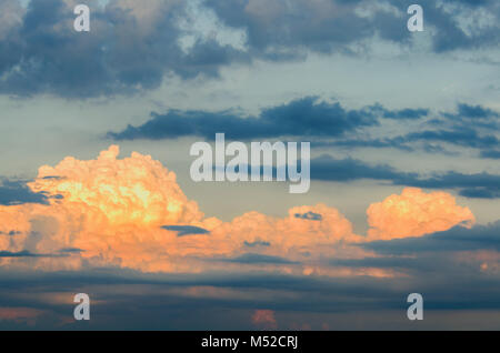 Sehr grosse Orange und Blau cumulus und spindrift Wolken, von der aufgehenden Sonne hervorgehoben, nachdem der Regen gegen den blauen Himmel Stockfoto