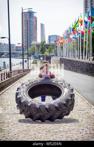 Foto von einer attraktiven jungen Frau, die mit einem Traktor Reifen in Rotterdam, die Niederlande Stockfoto