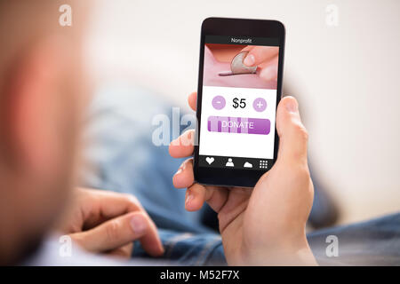 Person's Hand Handy mit Spende App auf dem Bildschirm Stockfoto