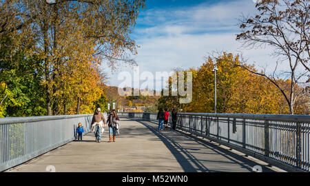 Bei den orangen und gelben Blätter in Herbstfarben eingerahmt, eine Familie mit ayoung Kind Spaziergänge entlang der Promenade über den Hudson, eine Brücke aus Stahl Stockfoto