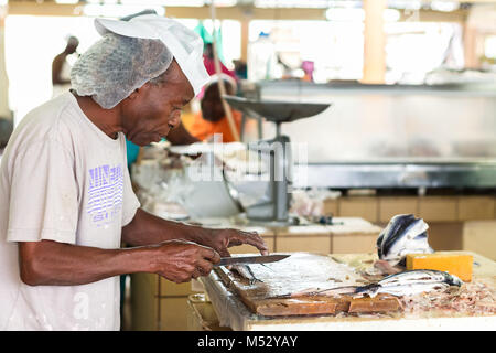 Bridgetown, Barbados - Januar 31th, 2018: Ein männlicher Arbeiter am Bridgetown Fischmarkt bereitet fliegende Fische zum Verkauf. Stockfoto