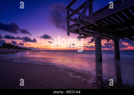 Sonnenuntergang über hölzerne Seebrücke auf dem Meer Strand Stockfoto