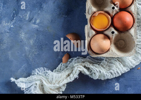 Gebrochene Eier mit sichtbaren Eigelb in einer Faltschachtel. Close-up mit kopieren. Moderne Ostern Konzept mit Kopie Raum Stockfoto
