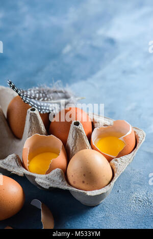 Rohe Hühnereier in der Craft-Packung. Close-up mit kopieren. Gebrochene Shell mit sichtbaren Eigelb. Stockfoto