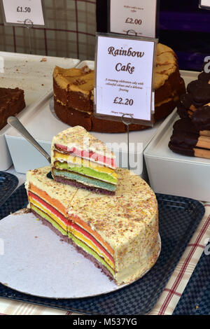 Eine bunte backen Regenbogen Kuchenscheiben zum Verkauf auf einem Marktstand verkaufen Köstlichkeiten und süßen Kuchen und Bäcker. Süße Backwaren zum Verkauf an. Stockfoto