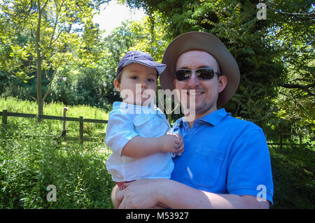 Ein Vater seine Kleinkind Sohn auf einem Spaziergang im Sommer draußen. Stockfoto