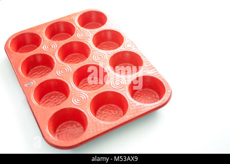 Leeres rotes Muffin Pan auf weißem Hintergrund Stockfoto