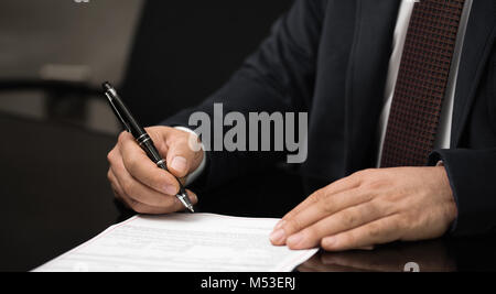 Makroaufnahme einer Hand eines Geschäftsmannes Unterzeichnung oder schreiben ein Dokument auf ein weißes Blatt Papier mit einem nibbed Füllfederhalter. Stockfoto