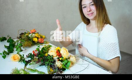 Nette junge Frau mit Floristen mit Lächeln und posieren mit Gest. Stockfoto