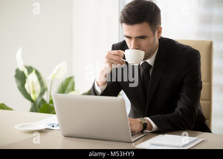Geschäftsmann Kaffee trinken bei der Arbeit im Büro Stockfoto
