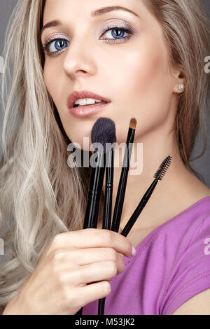 Blonde Schönheit weiblicher Stylist - visagist mit Make-up-Pinsel in der Hand Stockfoto