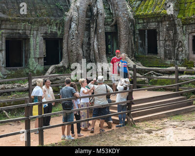 Touristen Warteschlange in der Linie zu Fotos der spung Baum an Ta Prohm Tempel in Angkor, Kambodscha nehmen Stockfoto