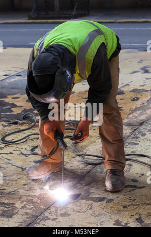 Ein Arbeiter Schweißen eine Stahlplatte auf einem New York City street. Stockfoto