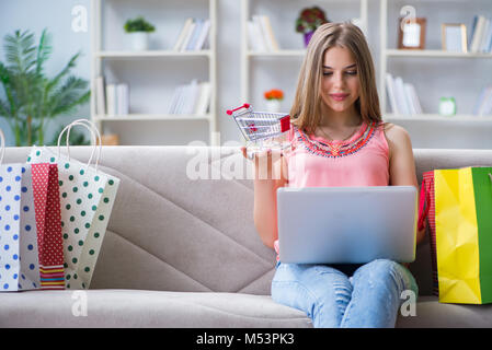 Junge Frau mit Einkaufstüten drinnen zu Hause auf dem Sofa Stockfoto