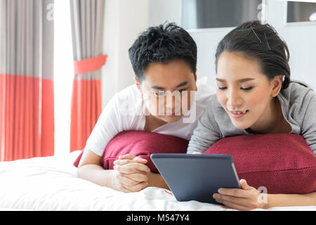 Paare mit Tablet auf dem Bett liegend Stockfoto