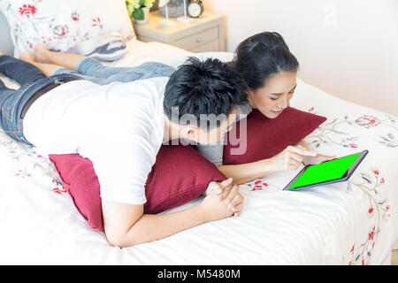 Paare mit Tablet auf dem Bett liegend Stockfoto