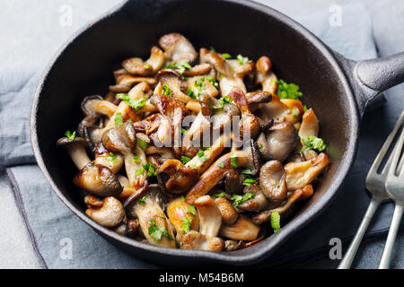 Gebratene Pilze mit frischen Kräutern in schwarzen gusseisernen Pfanne Stockfoto