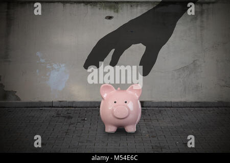 Close-up Silhouette Hand Herauf Sparschwein auf der Straße Stockfoto