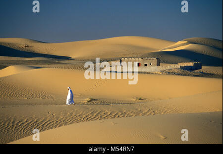 Algerien. In der Nähe von Nador. Die östliche Sand Meer. Grand Erg Oriental. Sahara. Traditionelle Häuser in der Oase. Beduinemann wandern. Stockfoto