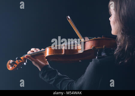 Violine zu spielen. Frau Violine zu spielen mit dem Rücken zur Kamera auf schwarzem Hintergrund Stockfoto