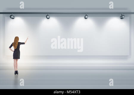 Geschäftsfrau drücken virtuelle Taste auf der Wand beleuchtet mit spotl Stockfoto