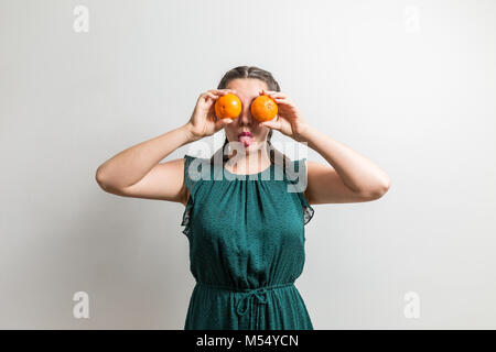 Süße Mädchen zeigt Zunge, während die Orangen wie Augen Stockfoto