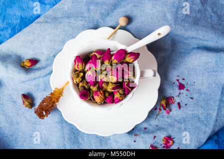 Rose Tee Blüten, die eine weiße Tasse Tee Stockfoto