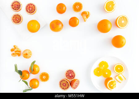 Zusammensetzung der Blutorangen, Orangen und Clementinen, ganz, halbiert, geschält und in Scheiben geschnitten auf Marmor, Porzellanteller und weißen backgroun angeordnet Stockfoto