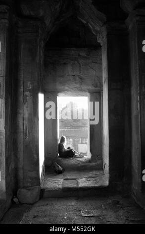 Junge weibliche im Eingang sitzen zu Angkor Wat Tempel, Sonnenlicht. Stockfoto