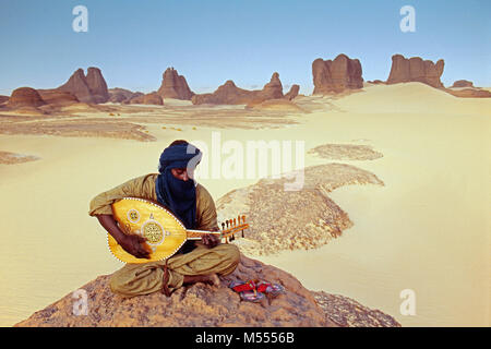 Algerien. In der Nähe von Tamanrasset. Tassili du Hoggar. Sahara. Mann aus Tuareg Stamm spielen Laute. Nomad. Stockfoto