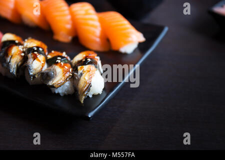 Aal und Lachs Sushi Sashimi auf schwarzem Teller mit leere Tabelle Stockfoto