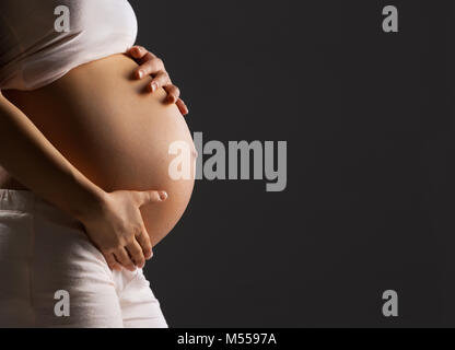 Schwangere Frau streichelt ihren Bauch Stockfoto