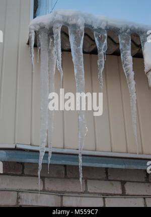 Gefährlich großen Eiszapfen auf dem Dach von einem Haus im Dorf Stockfoto