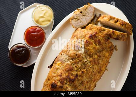 Top down Sicht auf hausgemachten Hackbraten mit Soßen auf Schwarzen Tisch Stockfoto