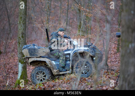 Junge Jäger auf ein Quad auf der Suche nach Spiel im Wald Stockfoto