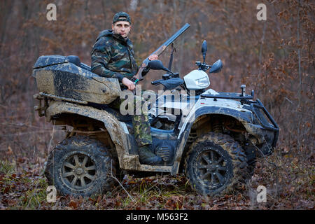 Junge Jäger auf ein Quad auf der Suche nach Spiel im Wald Stockfoto