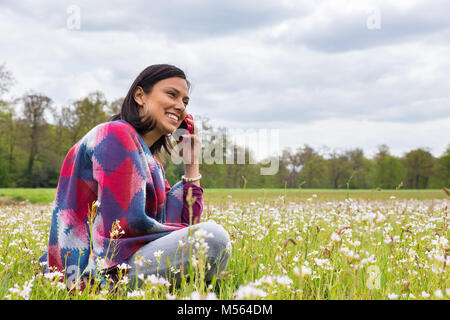 Frau sitzt in der Blumenwiese telefonieren Mobile Stockfoto